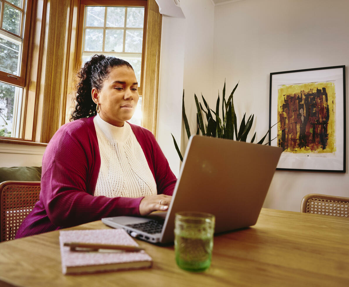 Female working on laptop on a table at home
