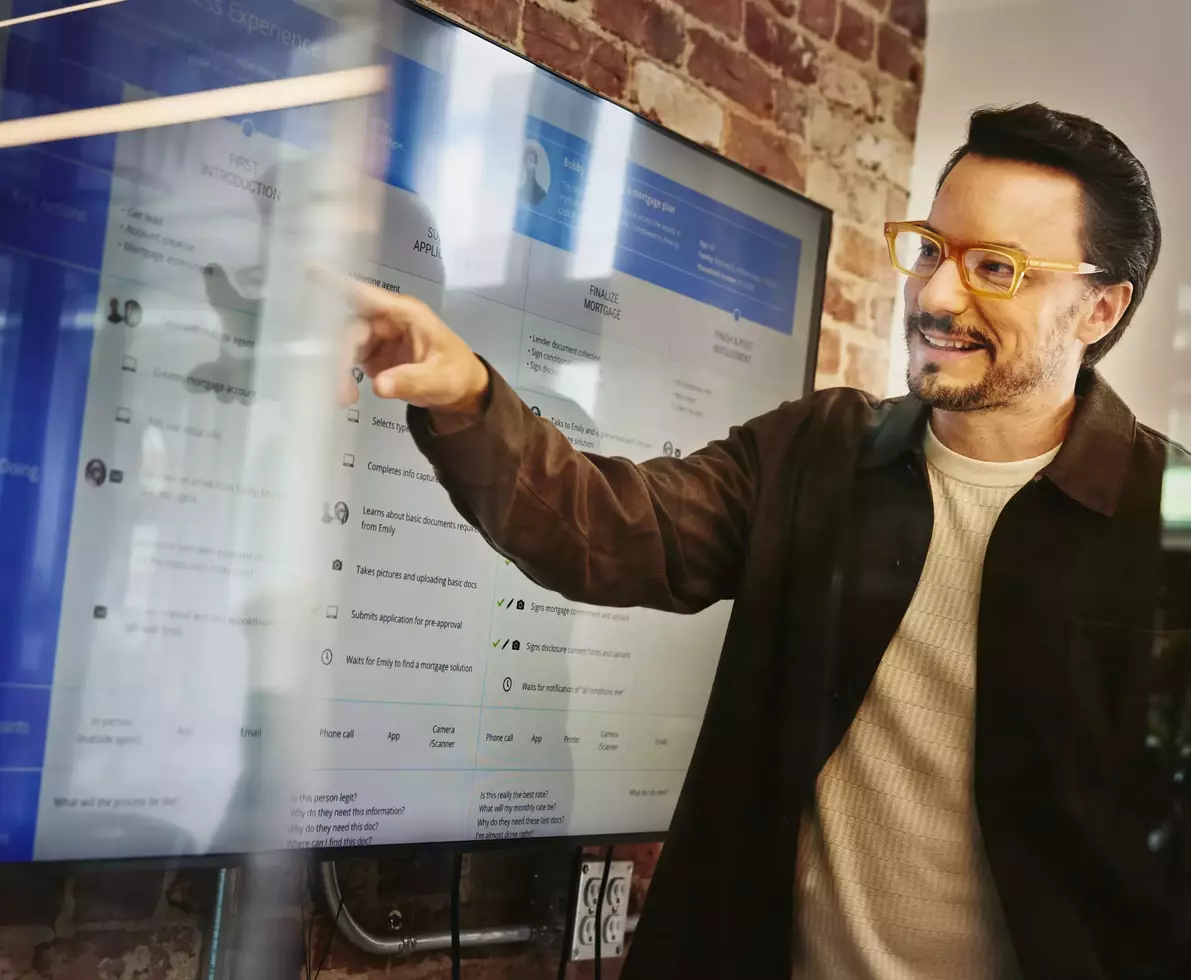 Male standing in front of a screen and pointing at data